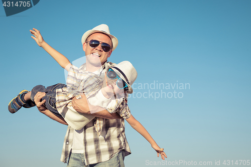 Image of Father and son playing on the field at the day time.