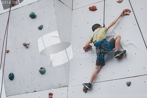 Image of little boy climbing a rock wall outdoor.