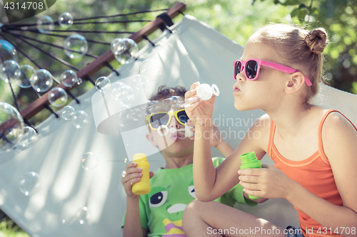 Image of Two happy children lie on a hammock and play with soap bubbles