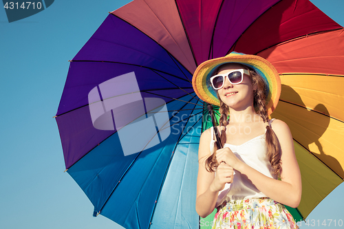 Image of teen girl with umbrella standing on the beach at the day time.