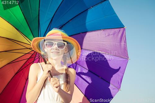 Image of Little girl with umbrella standing on the beach at the day time