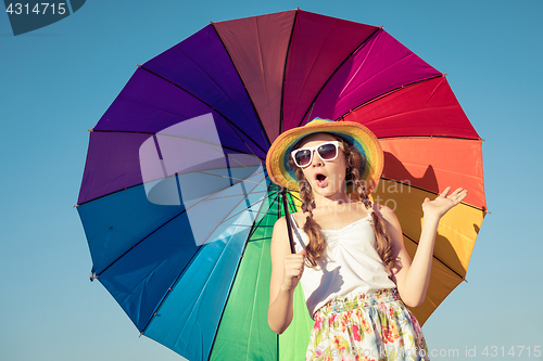 Image of teen girl with umbrella standing on the beach at the day time.