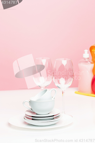 Image of Several plates, a kitchen sponges and a plastic bottles with natural dishwashing liquid soap in use for hand dishwashing.