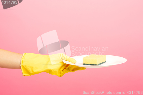 Image of Hands in yellow protective gloves washing a plate