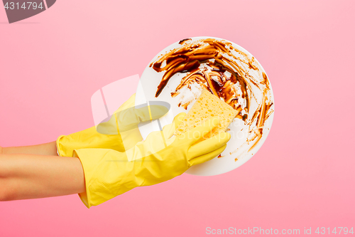 Image of Hands in yellow protective gloves washing a plate