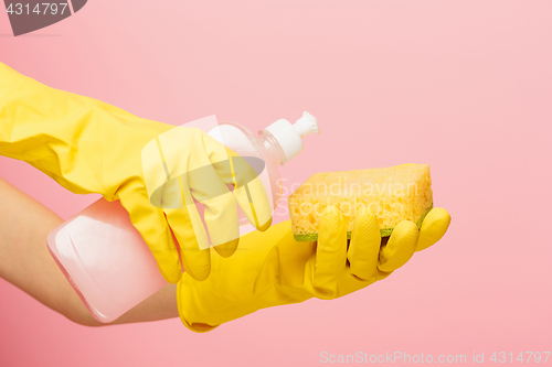 Image of The woman\'s hand cleaning on a pink background. Cleaning or housekeeping concept