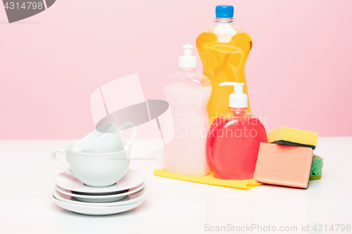 Image of Several plates, a kitchen sponges and a plastic bottles with natural dishwashing liquid soap in use for hand dishwashing.