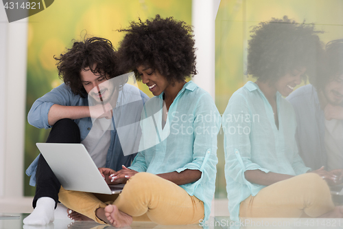 Image of multiethnic couple using a laptop on the floor