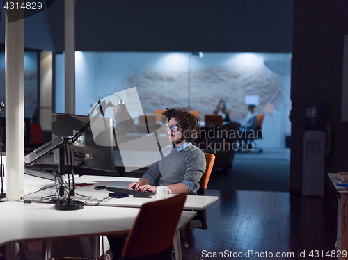 Image of man working on computer in dark startup office