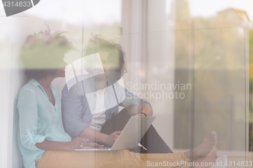 Image of multiethnic couple using a laptop on the floor