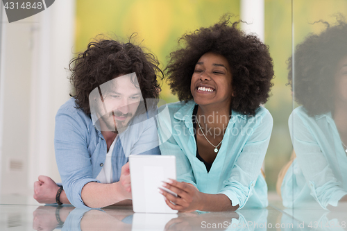 Image of Couple relaxing together at home with tablet computer