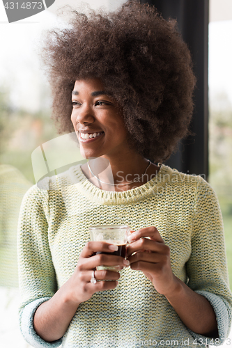 Image of African American woman drinking coffee looking out the window