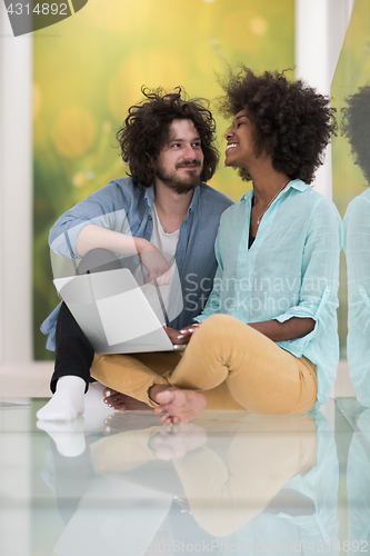 Image of multiethnic couple using a laptop on the floor