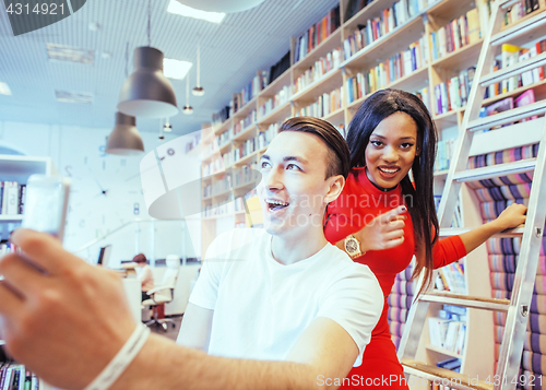 Image of couple students in univercity library, looking book, preparing t