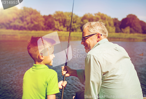 Image of grandfather and grandson fishing on river berth