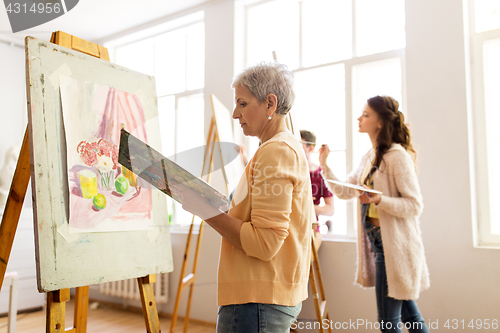 Image of woman artist with easel painting at art school