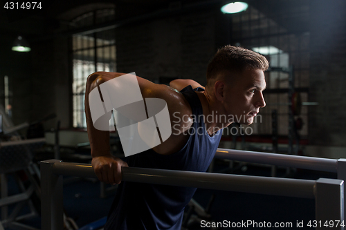 Image of man doing triceps dip on parallel bars in gym