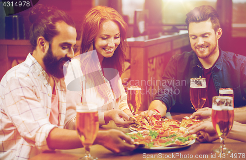 Image of friends eating pizza with beer at restaurant