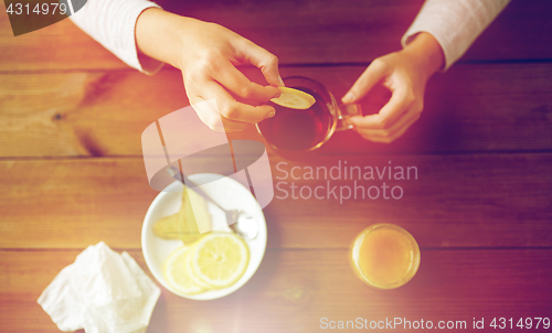 Image of close up of woman adding lemon to tea cup