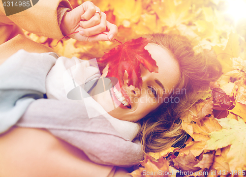 Image of beautiful happy woman lying on autumn leaves