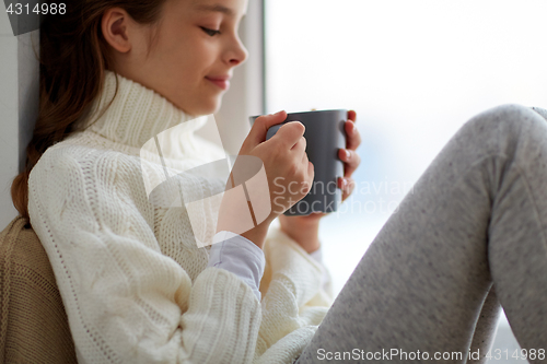 Image of girl with tea mug sitting at home window