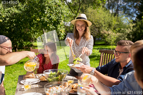 Image of happy friends having dinner at summer garden party