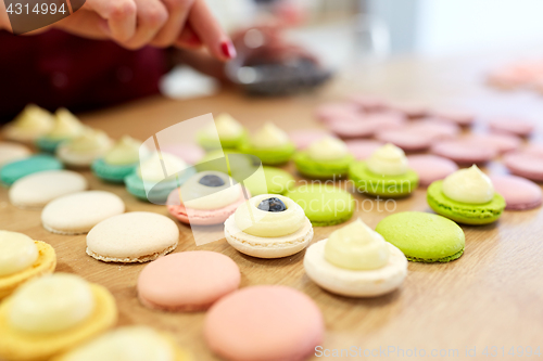 Image of chef decorating macarons shells at pastry shop