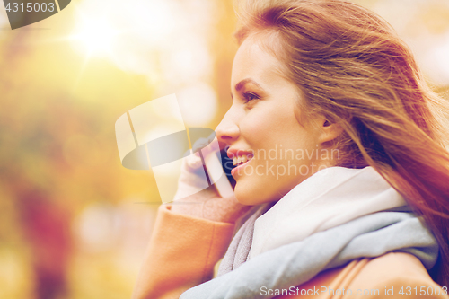 Image of woman calling on smartphone in autumn park