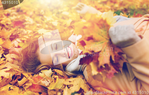 Image of beautiful happy woman lying on autumn leaves