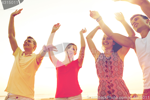 Image of smiling friends dancing on summer beach