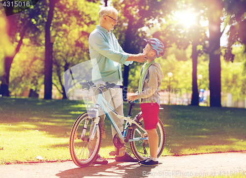 Image of grandfather and boy with bicycle at summer park