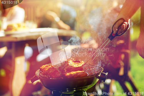 Image of man cooking meat on barbecue grill at summer party