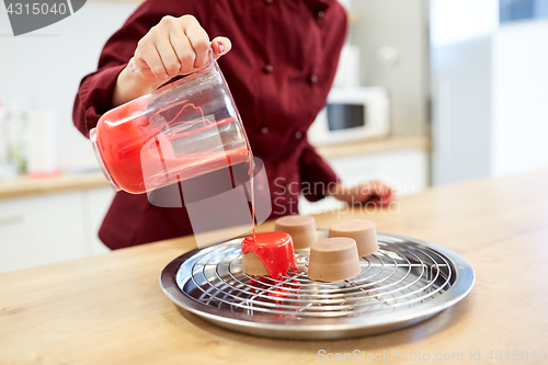 Image of chef with jug pouring glaze to cake at pastry shop