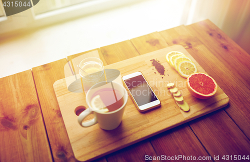 Image of smartphone with cup of lemon tea, honey and ginger