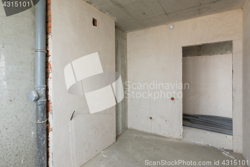 Image of Small kitchen in a new building, bare concrete and plastered walls, communications
