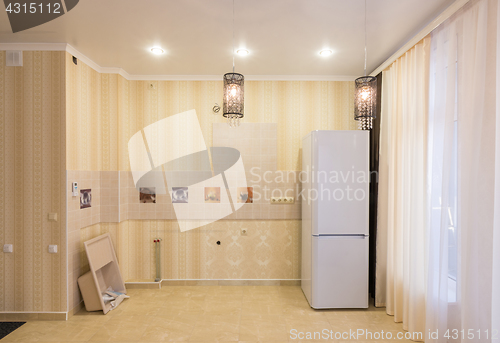 Image of Interior of an empty kitchen without furniture, there is a sink and a refrigerator