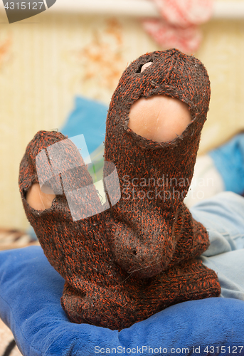 Image of Woolen socks with huge holes on the legs of a man