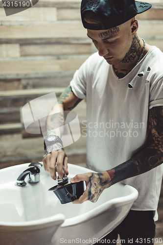 Image of Crop tattooed barber making foam