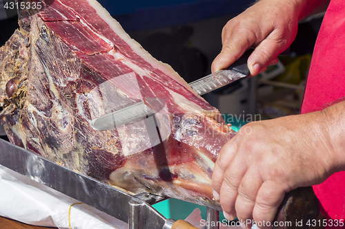 Image of Slicing dry-cured ham prosciutto on the street market