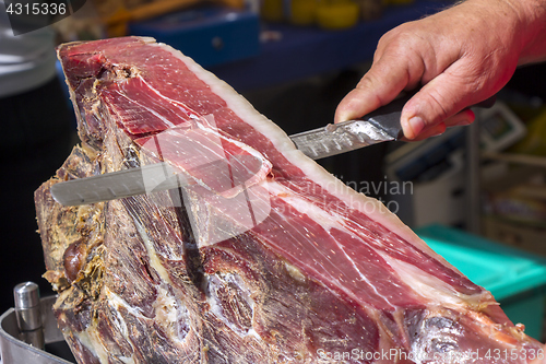 Image of Slicing dry-cured ham prosciutto on the street market