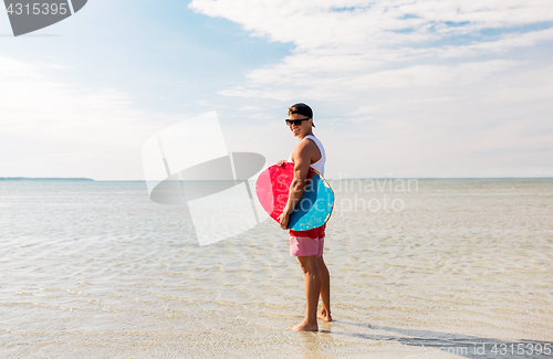Image of happy young man with skimboard on summer beach