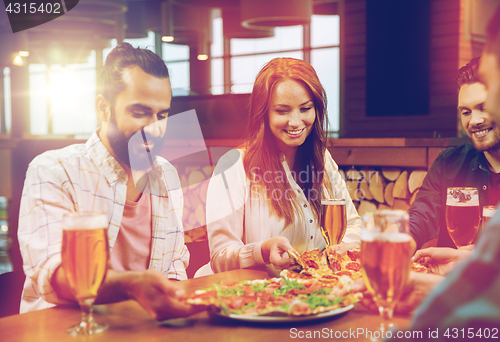 Image of friends eating pizza with beer at restaurant