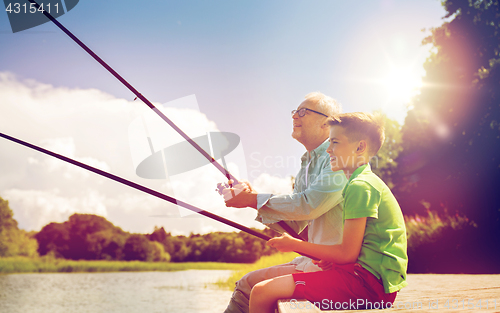 Image of grandfather and grandson fishing on river berth