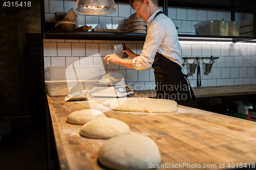 Image of chef or baker weighing dough on scale at bakery