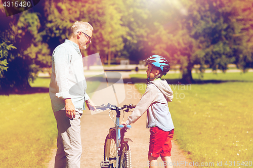 Image of grandfather and boy with bicycle at summer park