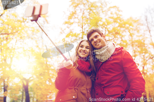 Image of couple taking selfie by smartphone in autumn park