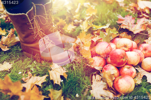 Image of woman feet in boots with apples and autumn leaves