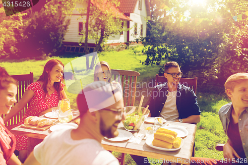 Image of happy friends having dinner at summer garden party