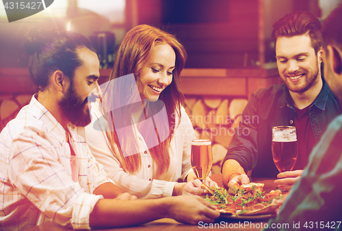 Image of friends sharing pizza with beer at pizzeria