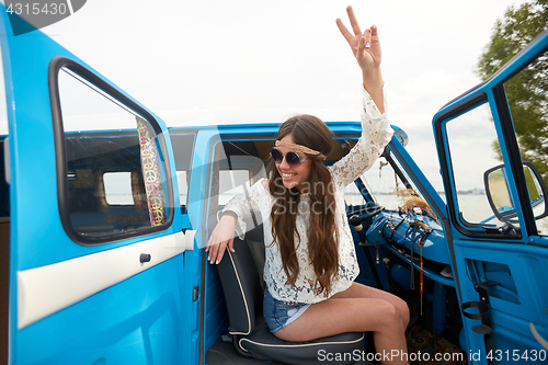 Image of happy hippie woman showing peace in minivan car